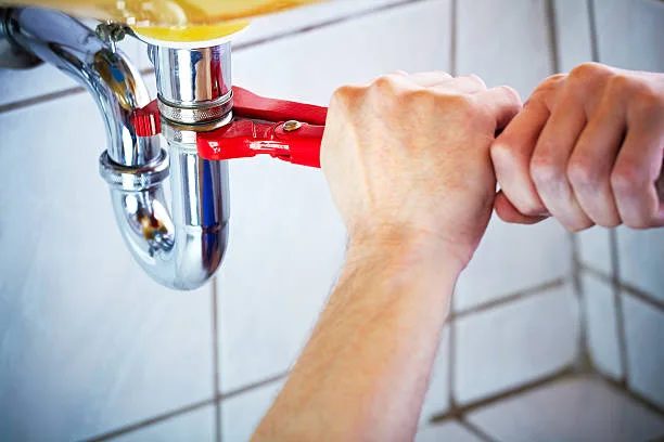Hands tightening a chrome sink drain connection