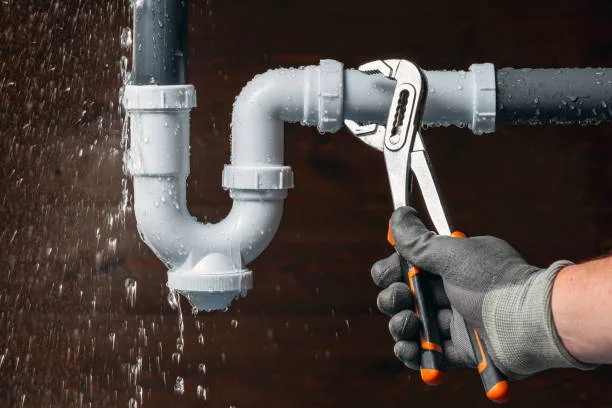 Leaking drain pipe with a wrench beside the connection