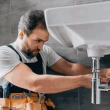 Plumber servicing the drain beneath a basin